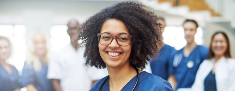 Woman smiling and standing in front of other healthcare workers