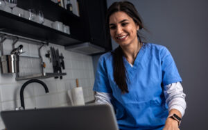 Nurse in blue scrubs working at computer