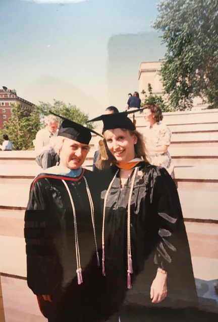 Two women in graduation caps and gowns at a college graduation.