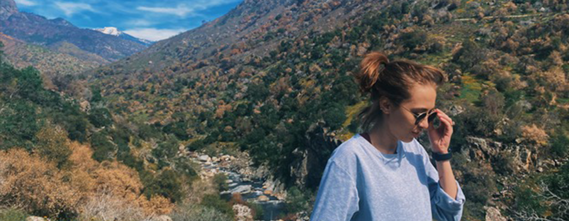 Briana Martinez on a hike with a mountain range behind her.