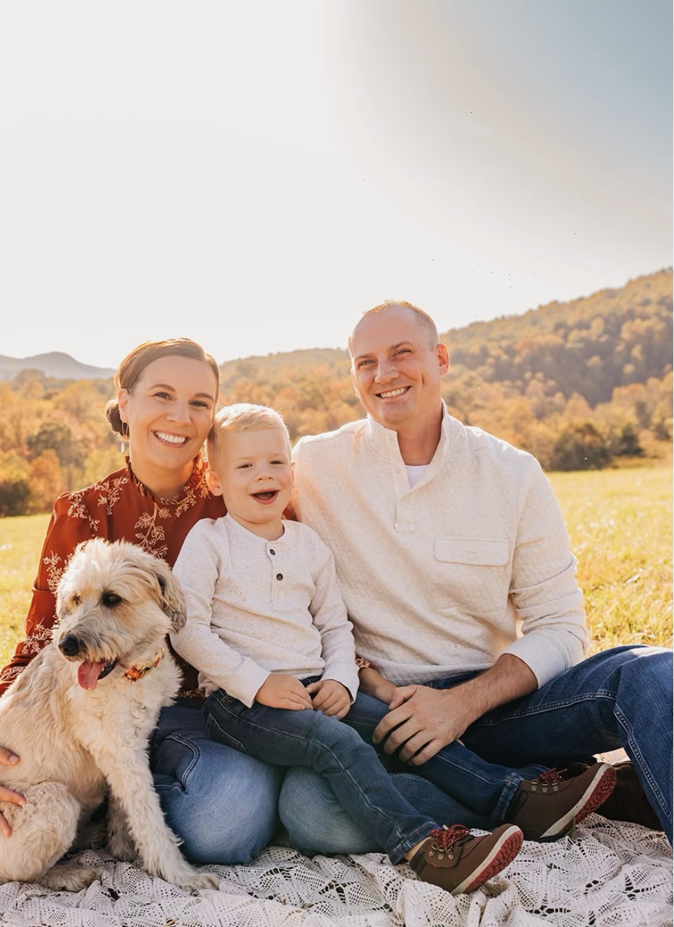 Brian Holben sitting in a field with his wife, son, and pet dog. 