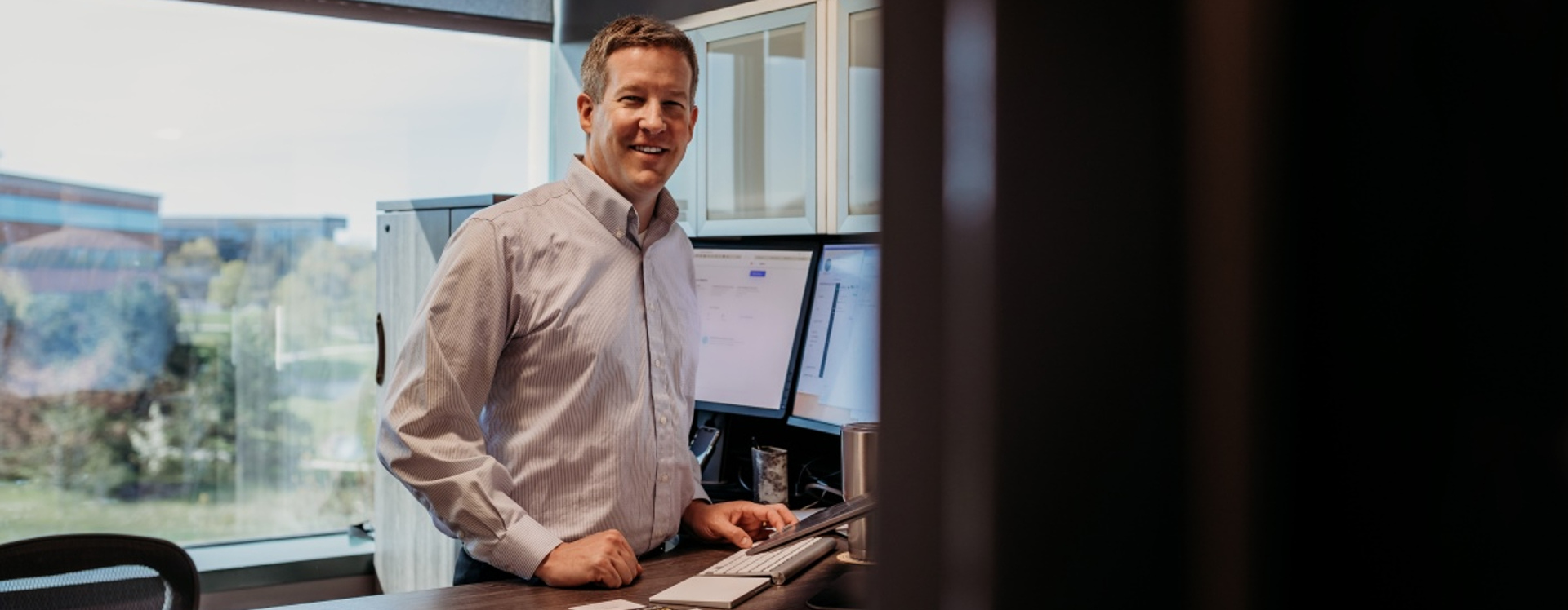 A professional photo of Michael Senkbeil standing near his desk in his office. Michael earned his online IST degree through UW Flexible Option.