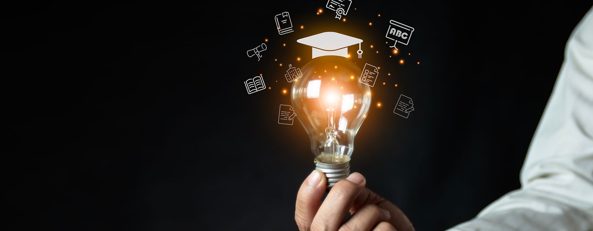 a man holding a light bulb showing his graduation cap