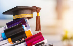 graduation cap on top of a pile of reports