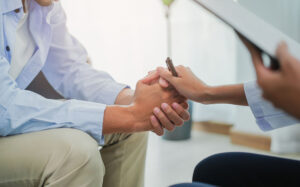 a counselor holding patient's hands in comfort