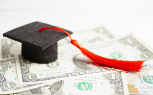 a graduation cap on top of dollar bills