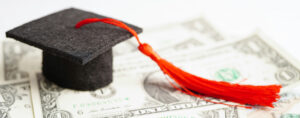 a graduation cap on top of dollar bills