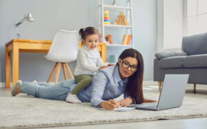 multi-tasking mom working on the laptop with her child sitting on her back