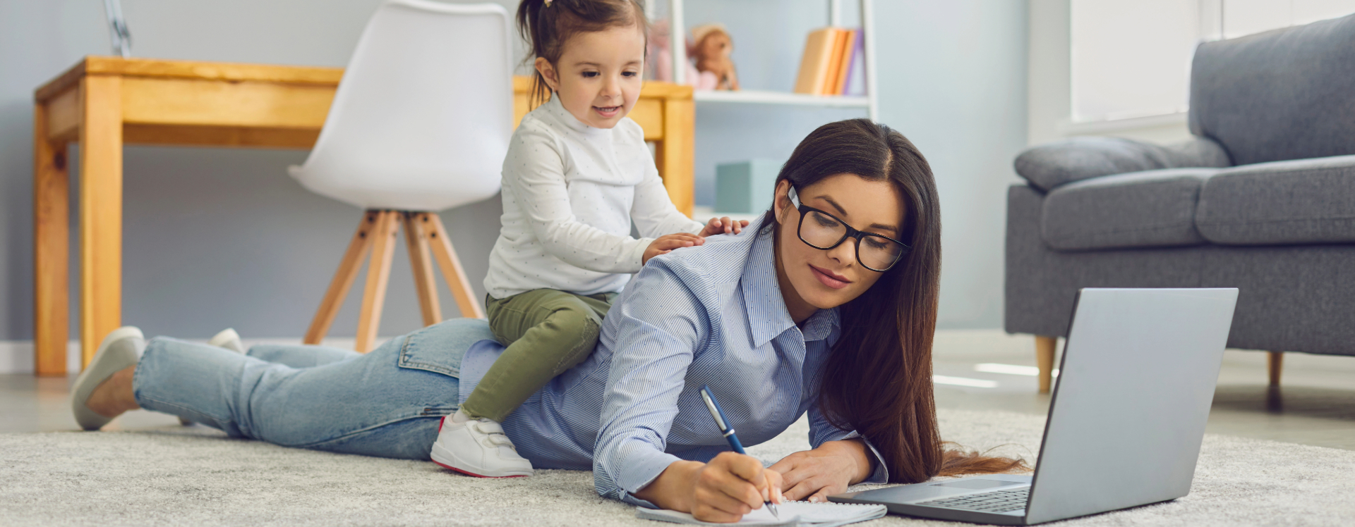 Busy mom multitasking on the computer with her child sitting on her back