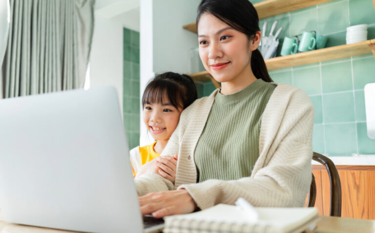 working mom studying online with her daughter sitting next to her