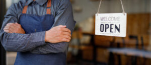 business person wearing a smock in front of a sign saying 