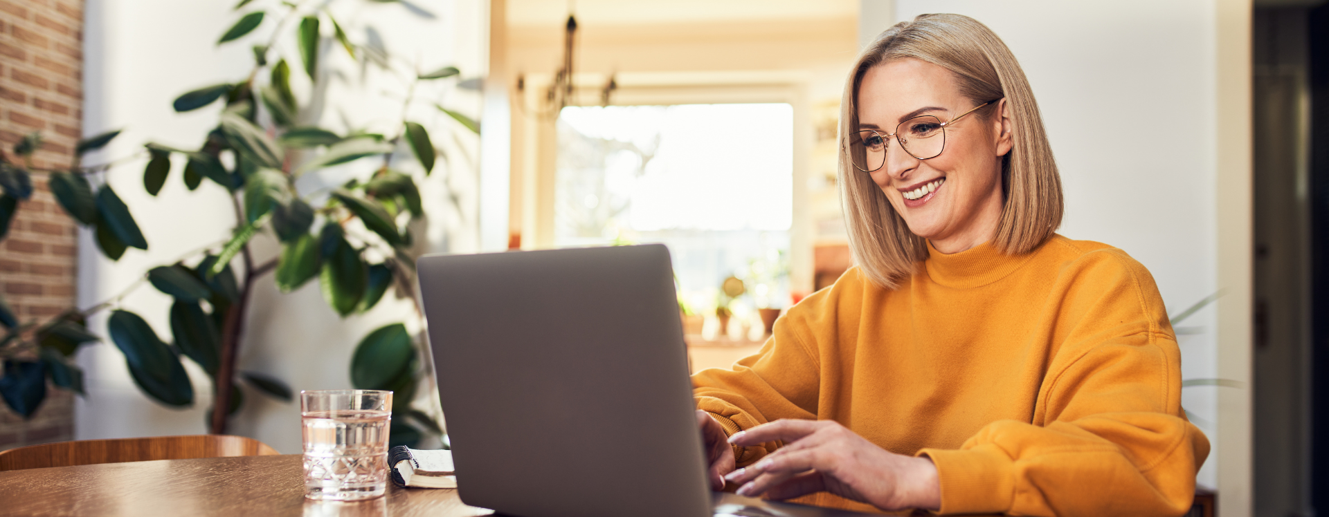 A woman smiles while using a laptop in her living room