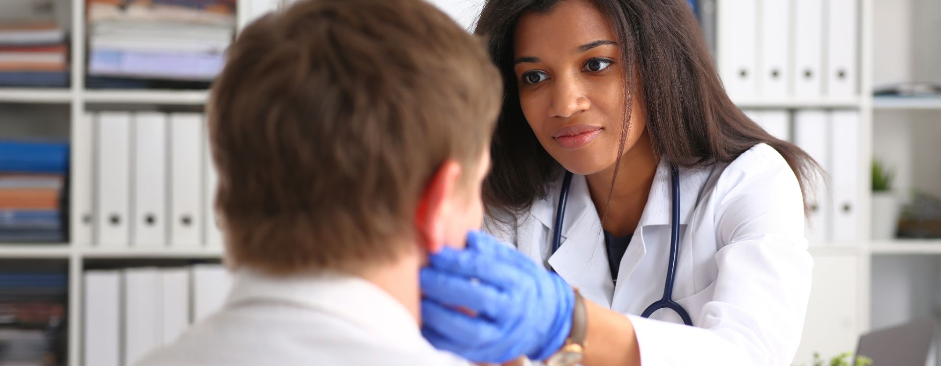 Female healthcare professional checks the lymph nodes of a male patient.