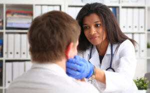 Female healthcare professional checks the lymph nodes of a male patient.